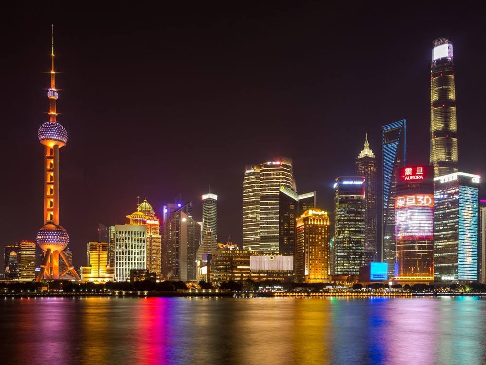 Los rascacielos de Pudong iluminados de noche desde el Bund de Shanghái