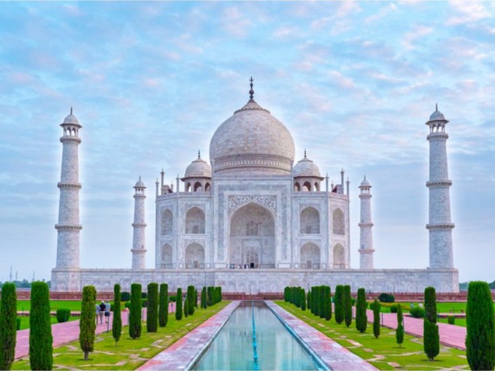 Taj Mahal al amanecer con sus jardines y el estanque reflejado, en Agra (India)