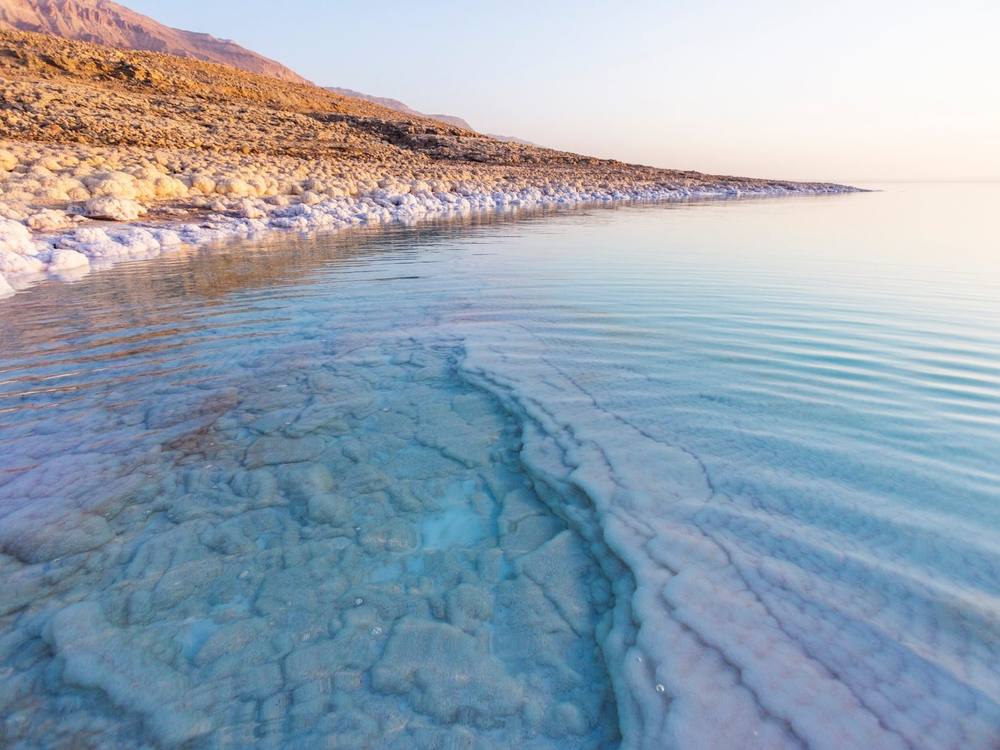 Orilla del mar Muerto con agua turquesa y costra de sal