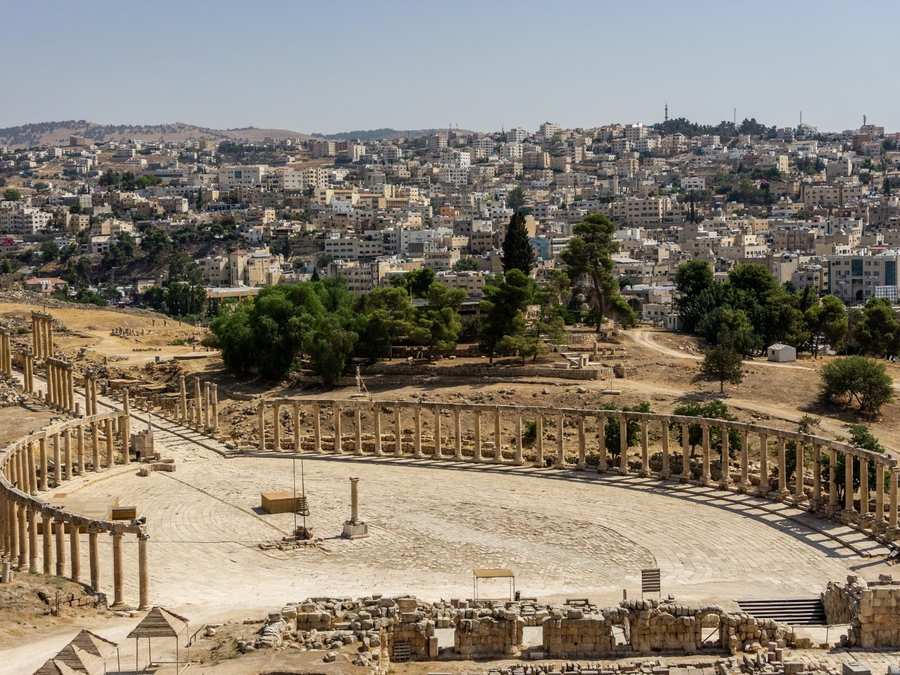 Plaza Oval y columnata romana de Jerash, con la ciudad moderna al fondo